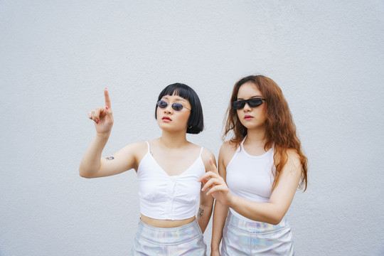 两位年轻的亚洲女性戴着墨镜触摸数字面板的肖像。未来技术概念。