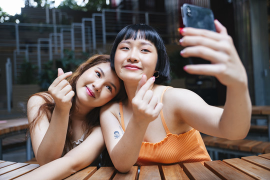 两位年轻亚洲女性一起用智能手机自拍的照片。