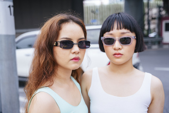 两位在街上戴太阳镜的时髦年轻亚洲女性的特写照片。