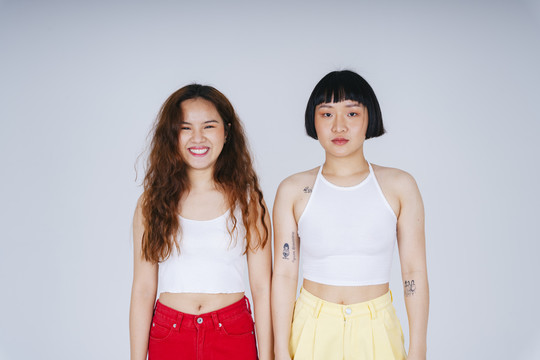 在白色背景上穿着白色背心的两名年轻亚洲女性的肖像。