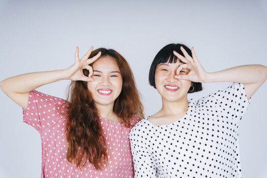 在白色背景上，两位年轻的亚洲女性用Ok手势的手的肖像。