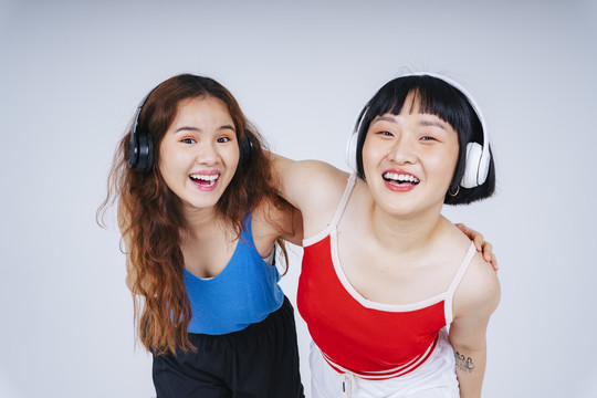 两位年轻的亚洲女性的肖像画，在白色背景下欣赏音乐和舞蹈。