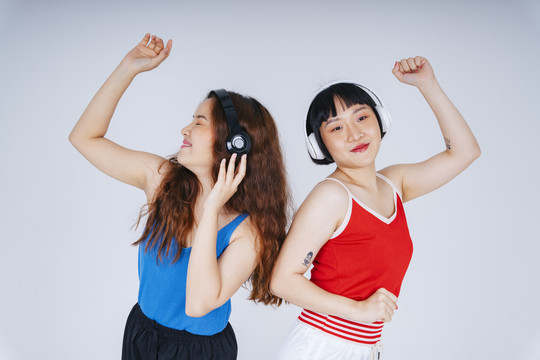 两位年轻亚洲女性的肖像画，在白色背景下欣赏音乐和舞蹈。