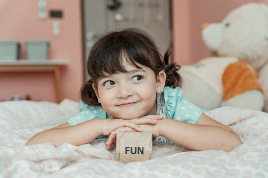 小女孩用玩具木块躺在床上的肖像。有趣的东西概念。