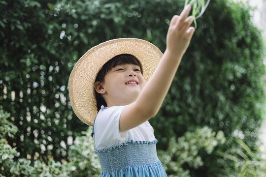 身穿蓝白色连衣裙、戴着帽子的小女孩的画像指向天空。