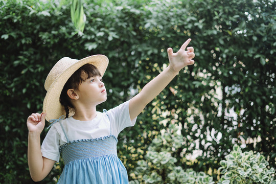 身穿蓝白色连衣裙、戴着帽子的小女孩的画像指向天空。