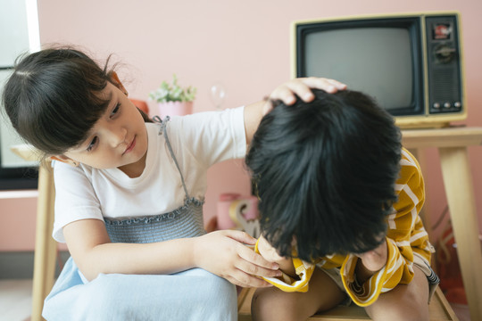 小妹妹拍了拍弟弟的头，试图安抚她那泪流满面的弟弟。