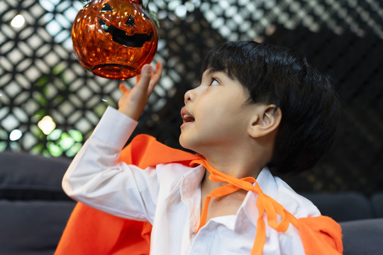 侧视图-亚洲男孩在万圣节派对上玩南瓜。