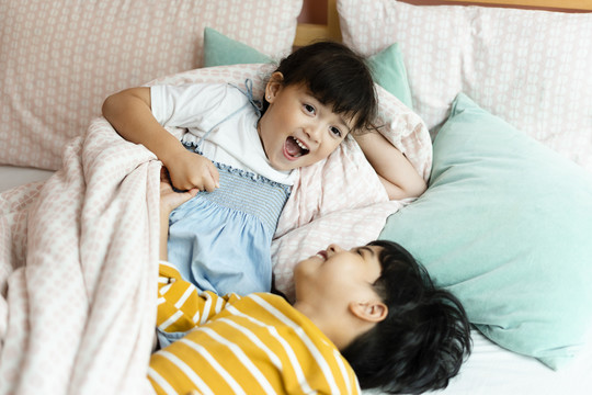 俯视图-快乐的男孩和女孩在床上玩耍。