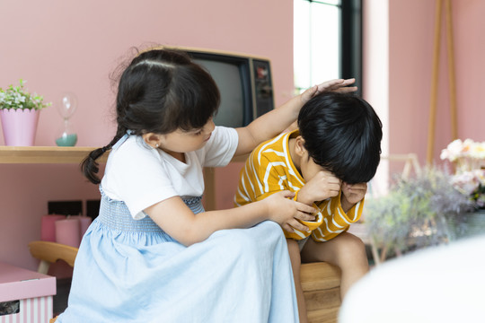 小妹妹拍了拍弟弟的头，试图安抚她那泪流满面的弟弟。