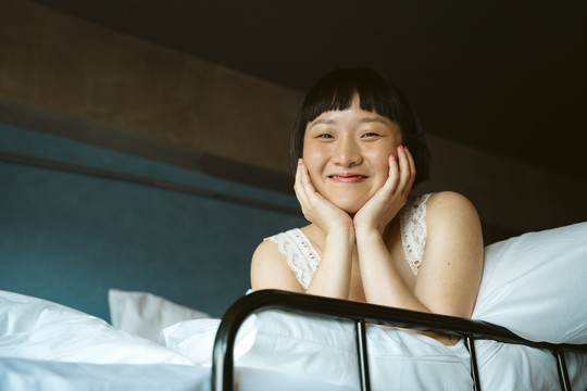 白色床上快乐的亚洲短发女人的肖像。