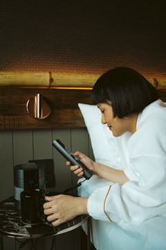 亚洲短发女人在卧室里用电视遥控器。