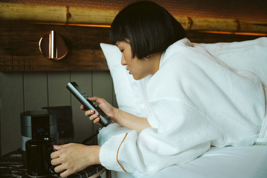 亚洲短发女人在卧室里用电视遥控器。