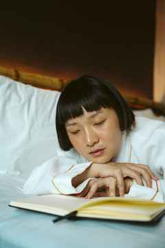 亚洲短发女人在床上看书后睡觉。