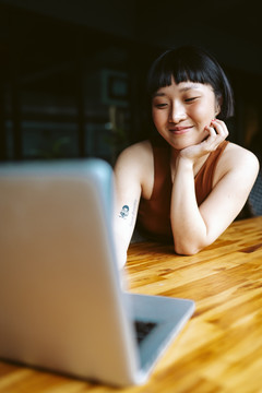 在咖啡馆里用笔记本电脑工作的亚洲短发女人。