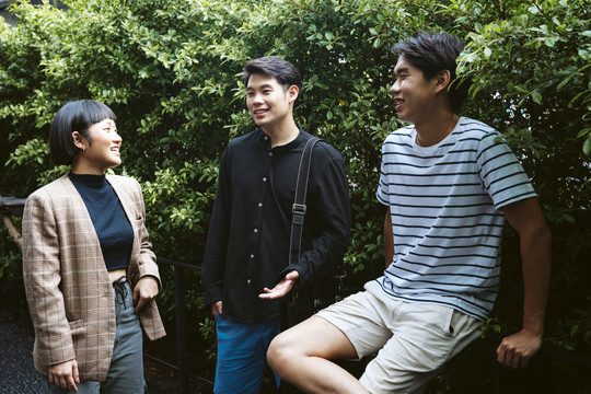 三个穿着休闲衬衫的亚洲年轻人在花园里。