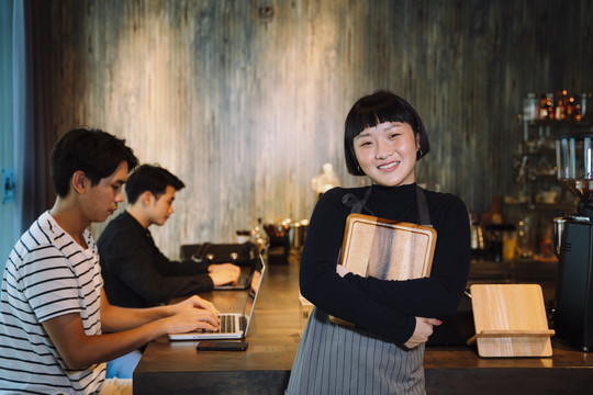 在自助餐厅拿着木制托盘的年轻亚洲短发女服务员的肖像。