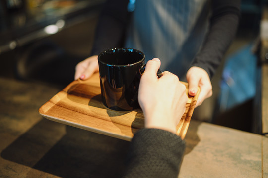 从咖啡馆的咖啡师手中拿热咖啡的顾客的特写手。