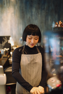 亚洲短发女咖啡师在咖啡馆煮热咖啡。