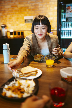 快乐的亚洲短发女人和朋友在餐桌旁共进午餐。