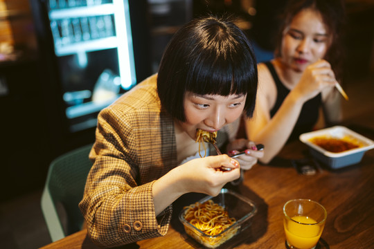 年轻的亚洲女商人在现代化的办公室里休息，一起吃午餐。