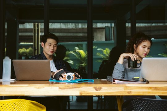 两名亚洲商人正在使用笔记本电脑。社会距离概念。