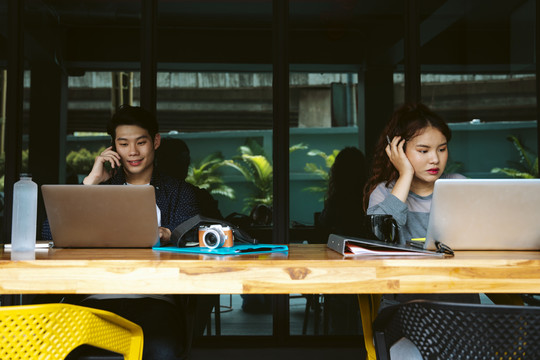 两名亚洲商人正在使用笔记本电脑。社会距离概念。