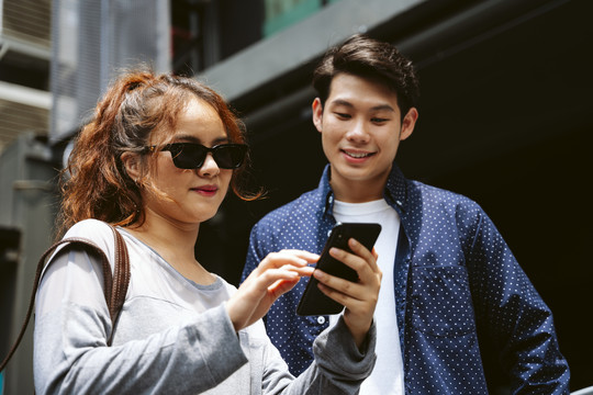 亚洲夫妇游客在智能手机上看数字地图。他们都在城里旅行。