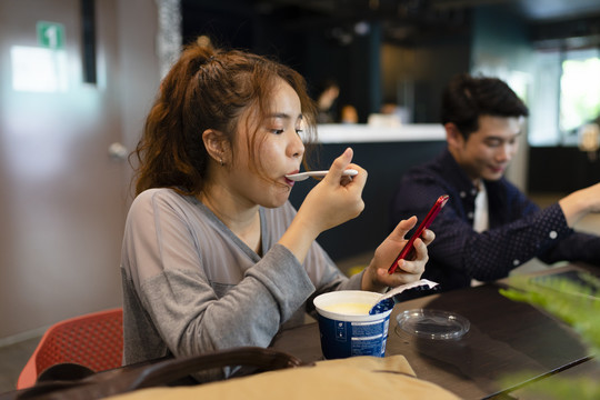 快乐的亚洲女人喜欢在酒吧吃午餐盒。