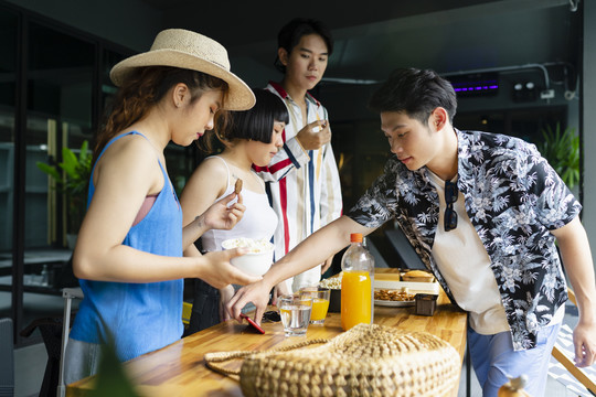 一群亚洲游客在酒店休息室的夏季派对上享用小吃。