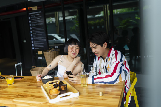 亚洲年轻人在智能手机上享受观看人流直播的乐趣。