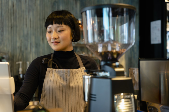 在咖啡馆的吧台后面煮咖啡的亚洲女咖啡师。