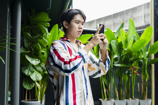 亚洲年轻人在酒店用智能手机拍照。