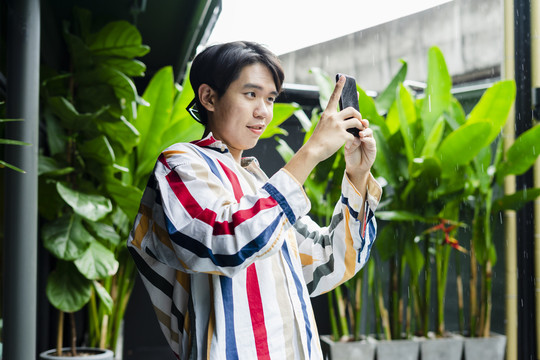 亚洲年轻人在酒店用智能手机拍照。