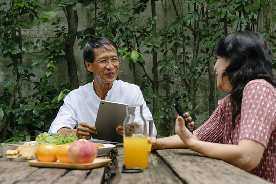 度假时，一对亚洲老夫妇在后院一起吃早餐。