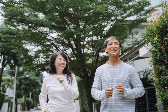 快乐的亚洲老年夫妇在公园户外慢跑锻炼。