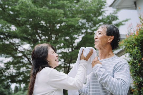 一对亚洲老夫妇在公园跑步后用毛巾洗脸。