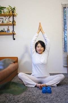 亚洲资深女性在家做瑜伽健身。健康生活方式理念。