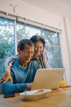 亚洲老年夫妇喜欢和笔记本电脑一起上网。