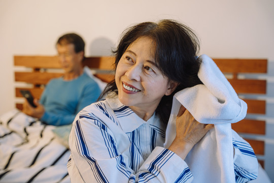 在卧室里用毛巾清洁头发的亚洲高级女性肖像。
