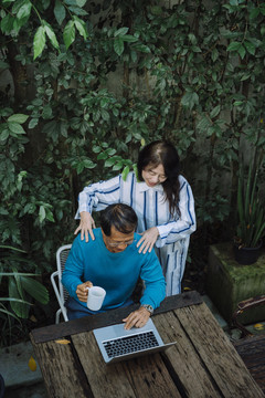 亚洲老夫妇在公园里，看着笔记本电脑，享受着浪漫的时刻。