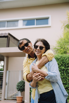 戴墨镜的亚洲老年夫妇相互拥抱。