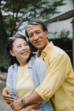 亚洲老年夫妇在后院室外拥抱的肖像。