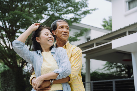 亚洲老年夫妇在后院室外拥抱的肖像。