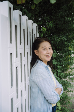 站在墙上做交叉手势的亚洲资深女性肖像。