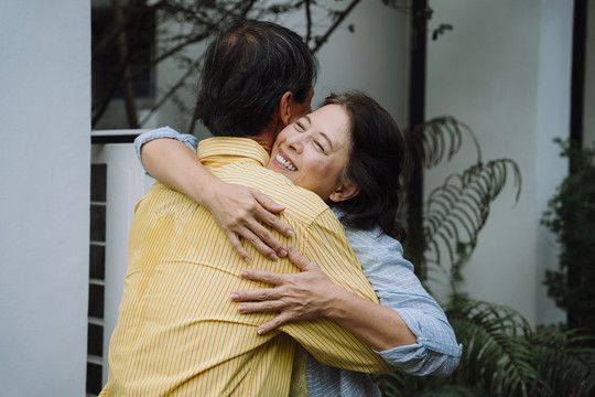 亚洲老年夫妇回家后拥抱他们的爱人。