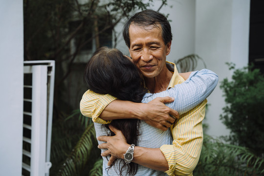亚洲老年夫妇回家后拥抱他们的爱人。