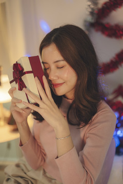 美丽的亚洲年轻女子黑发捧着她的圣诞礼品盒。