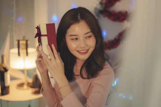 美丽的亚洲年轻女子黑发捧着她的圣诞礼品盒。
