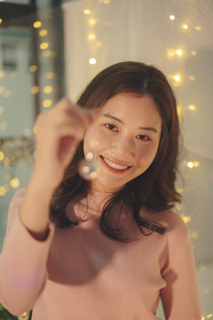 亚洲女孩在派对上举着圣诞玩具镜子球。